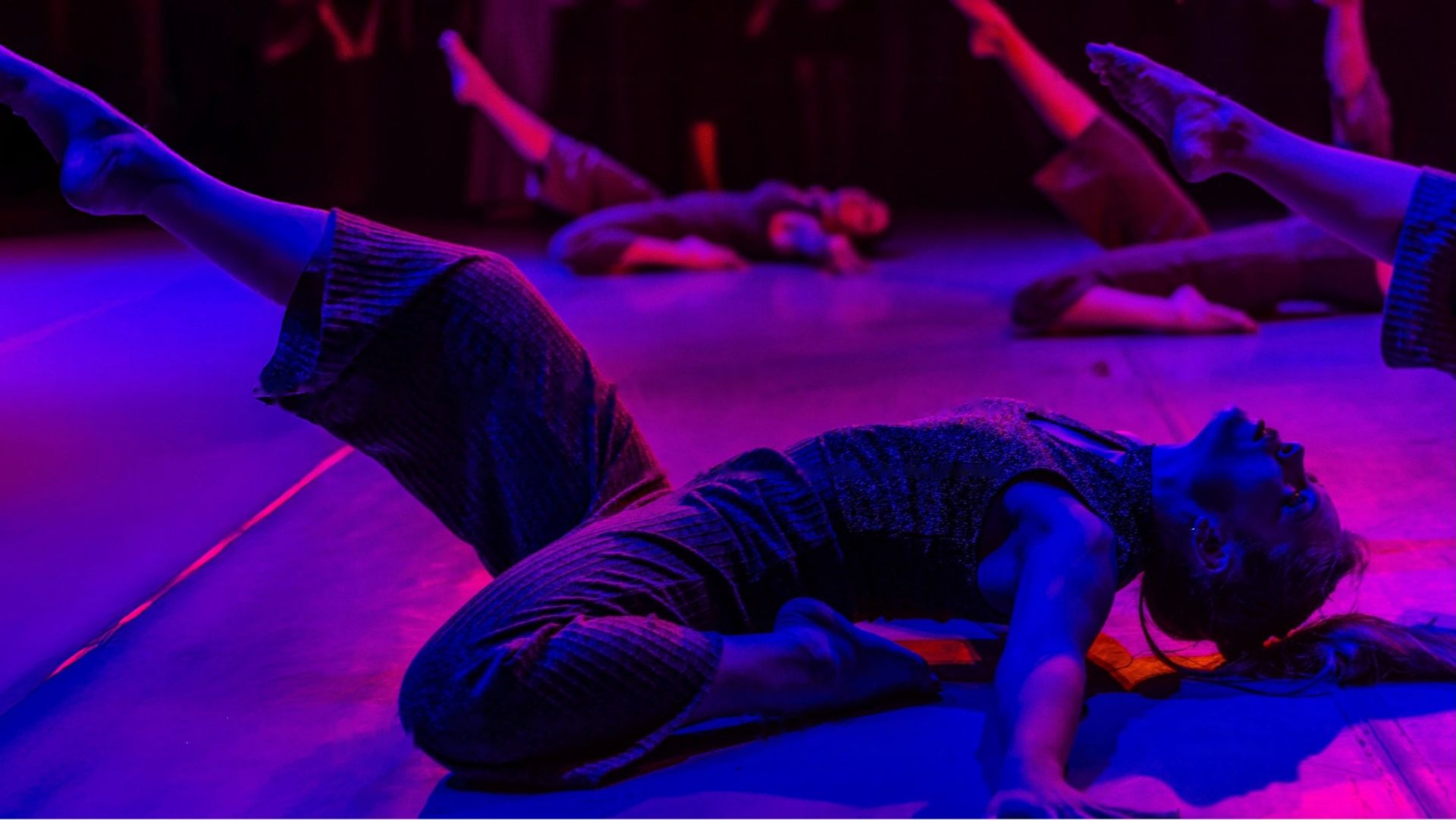 Danseuse allongée au sol, éclairage violet et magenta